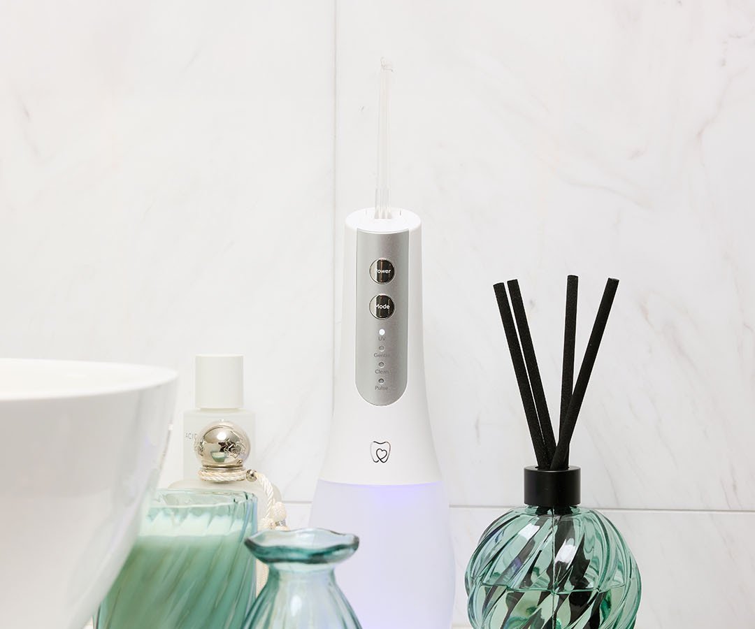 Spotlight Oral Care Water Flosser colocado en su base UV en una escena real de baño