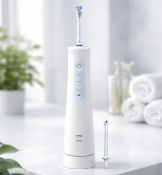 Irrigador dental portátil Oral-B AquaCare Series 4 sobre encimera de baño, con boquilla y fondo desenfocado premium, sin texto